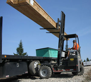 Palfinger CR55 4-Way Crayler Forklit shown lifting trusses off trailer.